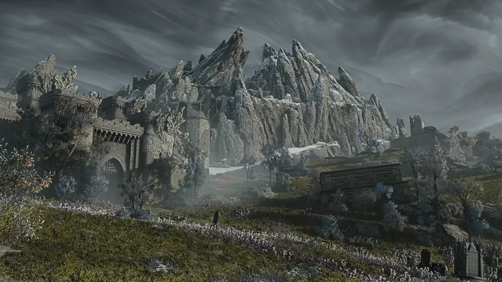 A landscape view of the realm of LimVeld from the game Elden Ring: Nightreign. There is the front gate of a castle left of the picture, a shack to the right of the image, and in the background is a large moutain in the background 